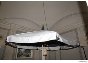 Evidence photograph showing a decorative airplane model suspended from the ceiling of an interior room. The model features white and black coloring and appears to be a vintage or mid-century design. The photograph documents the interior décor of what