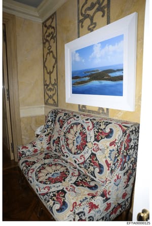 This is a photograph of an interior room space, likely from one of Epstein's properties, showing luxury furnishings and décor. The image captures a corner of a room with ornate wall treatments, an upholstered settee with elaborate patterned fabric, a