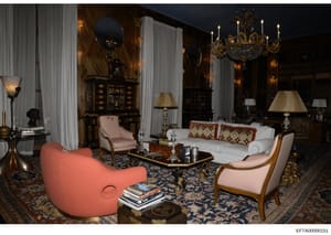 This is a photograph of an ornately decorated formal living room featuring high-end furniture, fine art, and luxury décor. The room displays classical and contemporary design elements including upholstered seating, crystal chandeliers, decorative mir
