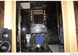 This is an evidence photograph showing a luxurious bathroom interior featuring high-end finishes including black marble walls, a vanity sink with illuminated mirror, and upscale fixtures. The image was collected as part of the investigation into Epst