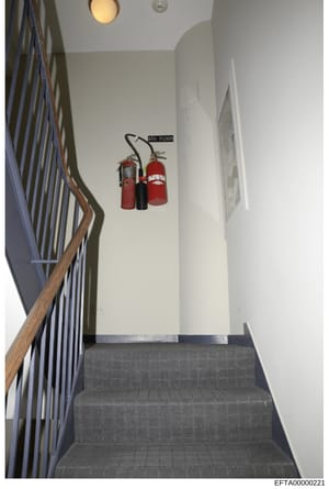 This is a photograph of an interior stairwell showing the fourth floor landing, featuring fire safety equipment mounted on the wall. The image documents the building's fire safety infrastructure and appears to be part of property documentation relate