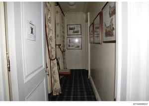 This is a photograph documenting an interior hallway in what appears to be one of Jeffrey Epstein's properties. The image shows a narrow corridor with decorative wall coverings, framed artwork, and furnishings. Such property photographs were typicall