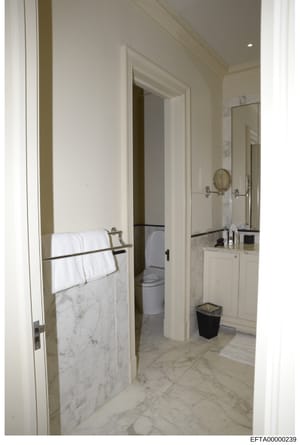 This is a photograph of a luxury bathroom interior, showing marble countertops, white cabinetry, and adjoining facilities. The image appears to be documentation of property interiors, likely from one of Jeffrey Epstein's residences as part of the inv