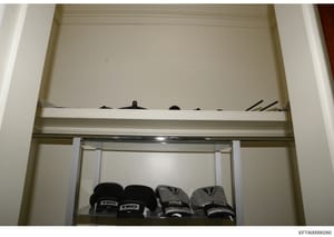 This photograph shows a built-in closet or storage shelf containing boxing gloves and other items. The image appears to be evidence documentation from a property search, showing the interior contents of a storage space. The presence of multiple pairs