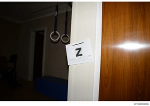 This is an evidence photograph from an FBI or law enforcement search, showing an interior room with gymnastics rings suspended from the ceiling and a white evidence marker labeled 'Z'. The marker indicates the location and item numbering for forensic