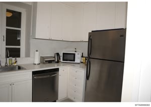 A photograph of a modern residential kitchen featuring white cabinetry, stainless steel appliances, and contemporary finishes. The image shows the kitchen layout and contents, likely taken as part of property documentation or evidence photography in 