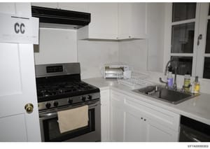This is an evidence photograph of a modern kitchen interior, likely from one of Jeffrey Epstein's properties. The image shows a clean, well-appointed kitchen with stainless steel appliances, white cabinetry, and granite countertops. It is marked with