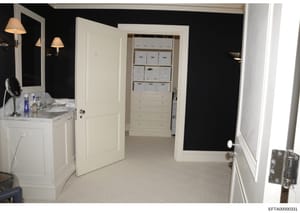 This photograph shows an interior view of a high-end bathroom featuring a marble vanity with sink, mirror with sconces, and an adjoining walk-in closet with built-in shelving and storage boxes. The image appears to be evidence documentation of proper