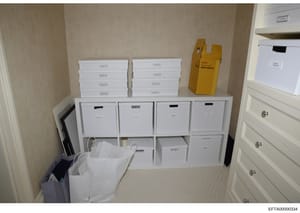 This photograph documents the interior of a storage closet or room containing numerous white filing boxes organized on shelving units, along with a yellow Kodak slide projector and other office equipment. The image appears to be evidence documentatio