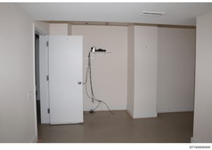 This is a photograph of an unfinished interior space showing white drywall partitions, exposed electrical wiring, and concrete flooring. The room appears to be in early-to-mid construction or renovation phase. The image was documented as evidence in 