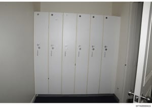 This photograph shows the interior of a room or closet containing six tall, white vertical cabinet or locker-style doors arranged side-by-side. Each door has similar hardware including a circular knob at the top and middle sections, with what appears