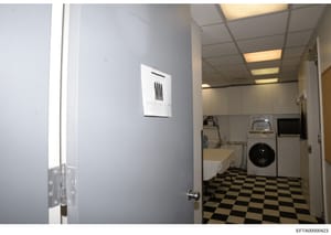 This photograph shows the interior of a laundry room, likely from one of Jeffrey Epstein's properties. The image depicts utility appliances including a washing machine, dryer, and utility sink, along with institutional-style fixtures and flooring. Th