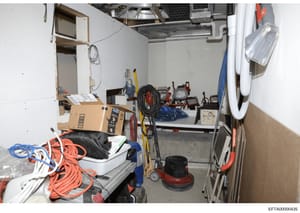 This is an evidence photograph showing the interior of a storage or utility room containing various maintenance and construction equipment, tools, and supplies. The image appears to be part of a property inventory or evidence documentation related to