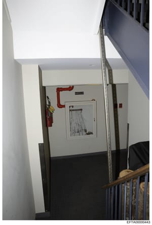 This is an evidence photograph showing an interior hallway or corridor in what appears to be a commercial or residential building. The image documents utility infrastructure including a red pipe labeled 'SUISCELLAR,' a fire extinguisher mounted on th