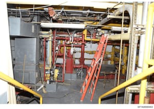 This photograph shows an interior mechanical or equipment room containing extensive red and yellow piping infrastructure, HVAC components, and industrial systems. The image appears to be documentation of building mechanical systems, possibly from one