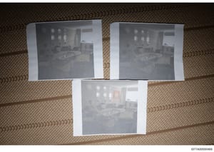 This document shows three black-and-white photographic prints arranged on a woven textured surface (likely carpet or fabric). The three images appear to be near-identical photographs of an interior room featuring decorative plates on walls, furniture