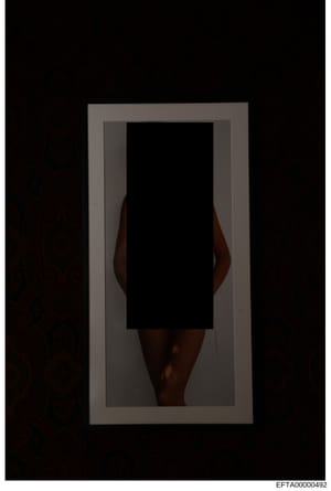 This is an evidence photograph showing a portrait of an individual with their face redacted or obscured. The photo appears to be a full-body or partial-body image taken against a neutral background, typical of investigative documentation. The large b