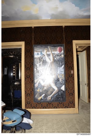 This is an evidence photograph documenting the interior of a residence, showing a large framed artwork depicting a nude female figure suspended in air against a cityscape background, hanging on ornate brown damask wallpaper. The image captures the de