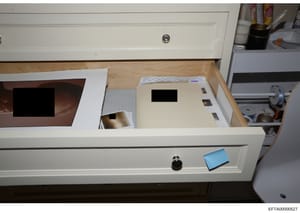This is a forensic evidence photograph showing an open white desk with multiple drawers containing various documents and materials. The image appears to be from a property search or evidence collection, with items including folders, envelopes, and ot