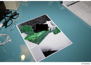 This is an evidence photograph showing a document or photograph laid on a turquoise surface, featuring black-and-white imagery with bright green marker annotations overlaid on portions of the image. Large sections are redacted with black bars. The ph