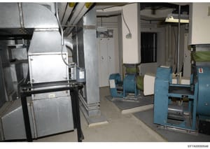 This is a photograph of an industrial or institutional basement/utility space containing large HVAC equipment, boilers, and other mechanical systems. The image appears to be evidence documentation from the investigation, showing the interior infrastr