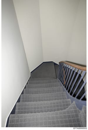 This is a photograph of an interior staircase with gray carpeting and wooden handrails, showing the architectural interior of what appears to be a residential or commercial property. The image is part of evidence documentation related to the Epstein 