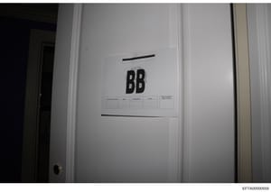 This is an evidence photograph showing a white interior door marked with large black letters 'BB' and attached documentation forms. The label and forms suggest this door was part of a systematic search and cataloging process during the investigation,