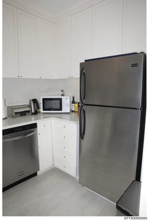 This is a photograph of a modern kitchen interior, showing appliances and cabinetry. The image appears to be evidence documentation from a property search or seizure, likely taken during the investigation to record the condition and contents of a res