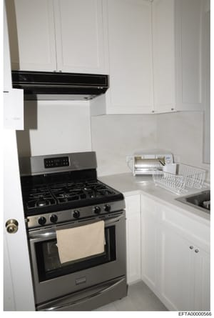 This photograph documents a kitchen interior featuring modern stainless steel appliances, white cabinetry, and contemporary fixtures. The image appears to be part of property documentation, likely from one of the residences involved in the Epstein in