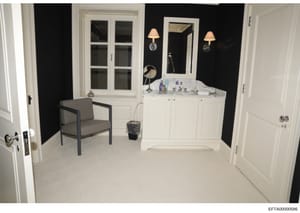 This is a photograph of an upscale bathroom interior featuring a large white vanity with marble countertop, dual wall sconces, and contemporary decor. The room displays high-end finishes consistent with luxury residential property documentation, like