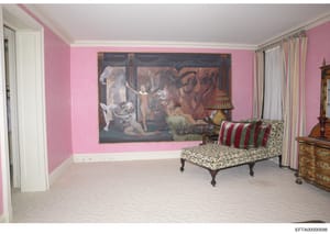 This is a photograph of an elegantly furnished bedroom interior, featuring distinctive pink walls, a large classical painting, period furniture including an ornate chaise lounge, decorative lamps, and fine furnishings. The image appears to be part of