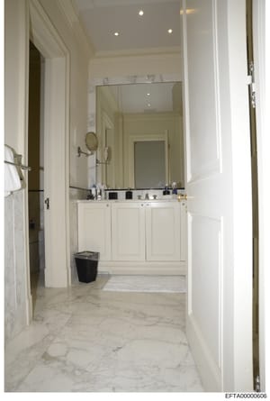 This is a photograph of an upscale bathroom interior, likely from one of Jeffrey Epstein's properties. The image shows a spacious, elegantly designed bathroom with high-end finishes including marble flooring, a large mirror, white cabinetry, and rece