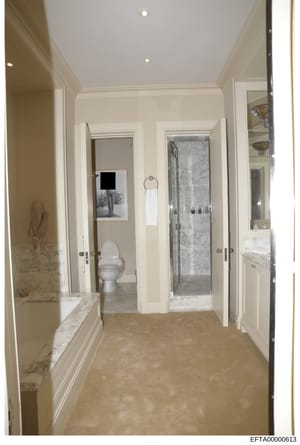 This is a photograph of an upscale bathroom interior featuring marble countertops, dual vanities, a walk-in shower, and toilet facilities. The image appears to be evidence documentation from one of Jeffrey Epstein's properties, showing the high-end r