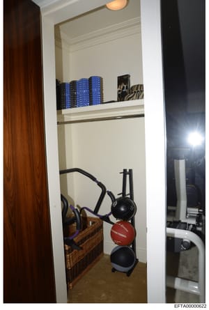 This photograph shows a closet or storage area containing exercise equipment, including medicine balls, resistance bands, and hair styling tools. The image appears to be documentation of a residential property's interior, likely from an evidence or p