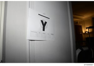 Evidence photograph showing a white interior door with a large letter 'Y' and what appears to be redaction marks or markings. Below the letter is a partially visible table or form labeled 'Search Personnel Name' with columns for Agency, Contact Numbe