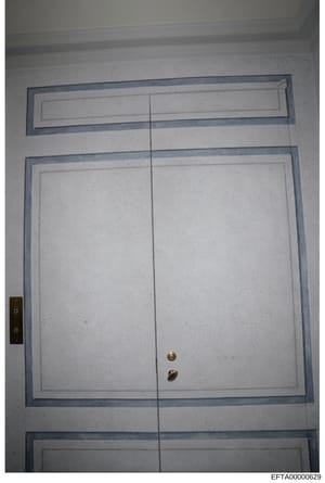 This is an evidence photograph showing the interior of a double-door entrance or closet with white panels, blue-gray frame trim, brass knobs, and an electronic keypad or intercom panel mounted on the left side. The photograph documents the physical s