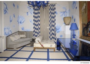 This is a professional interior design rendering or photograph showcasing a formal living room or sitting area featuring coordinated blue and white décor elements. The space displays high-end furnishings including a gray upholstered sofa, decorative 