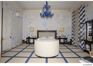 This photograph shows an interior design rendering or mockup of an opulently decorated bedroom featuring blue and white chinoiserie-style wallpaper, a distinctive circular white bed structure, luxury furnishings, and high-end design elements. The ima