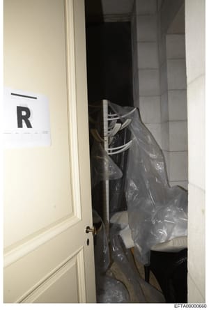 This is an evidence photograph showing the interior of a room or closet space containing electrical/HVAC equipment covered in plastic sheeting. A white evidence marker labeled 'R' is visible on the left side of the doorframe, indicating this photo wa