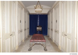 This photograph documents the interior of a luxury property, showing an elegantly appointed hallway with classical architectural details. The image features a billiards table with a red leather surface positioned in the center of the space, flanked b