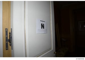 This is an evidence photograph showing an interior doorway with a white evidence marker displaying the letter 'N' attached to the wall. The marker includes a scale and reference grid used in forensic documentation. The photo appears to be taken durin