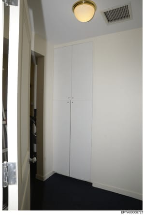 This is an evidence photograph showing the interior of a closet or small storage room with white built-in cabinetry. The image captures the room's layout, fixtures, and finishes as part of the investigation's documentation of properties associated wi