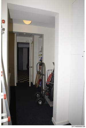 This is an evidence photograph showing an interior hallway or utility closet space in what appears to be a residential property. The image depicts stored equipment including dollies, a red stroller, and various maintenance items. The space has white 