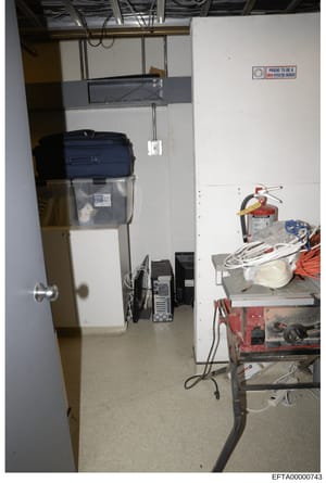 This is an evidence photograph showing the interior of a utility or storage room containing various mechanical and electrical equipment, tools, and supplies. The room appears to be a basement or utility space with exposed infrastructure including cei