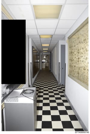 This photograph depicts an interior hallway, likely from one of Epstein's properties, showing a narrow corridor with distinctive black-and-white checkered tile flooring, recessed ceiling lights, white walls, decorative framed panels on the right wall