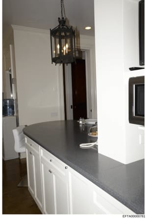 This is an interior photograph of a modern kitchen space, likely from one of Jeffrey Epstein's properties. The image shows a contemporary kitchen design with a large island counter featuring white cabinetry, dark countertop, and decorative black pend