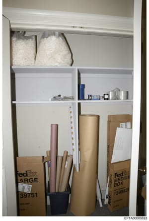 This is an evidence photograph showing the contents of a closet or storage space, featuring stacked boxes (including FedEx shipping boxes), rolls of material, bags of what appears to be packing peanuts or similar materials, and various storage contai