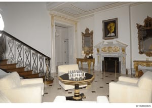 This is a photograph of an opulently decorated interior space, likely part of one of Jeffrey Epstein's residences. The room features neoclassical design elements including a grand marble fireplace with gilt ornaments, baroque mirrors, fine upholstere