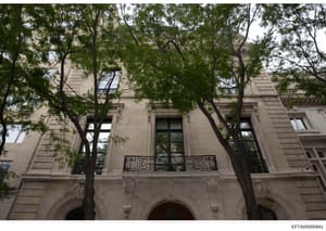 This photograph depicts the exterior facade of a Haussmann-style Parisian townhouse, featuring classic 19th-century French architectural elements including ornamental stonework, wrought iron balconies, and tall windows. The image is likely documentat