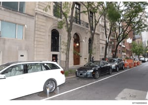 This is a photograph of a multi-story residential building in Manhattan, showing the street-level facade with elegant architectural details, parked luxury vehicles, and tree-lined sidewalk. The image appears to be documentary evidence related to prop